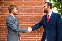 Two formally dressed men shaking hands in the street
